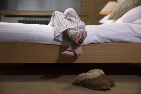 womans legs wearing pyjamas hanging off bed