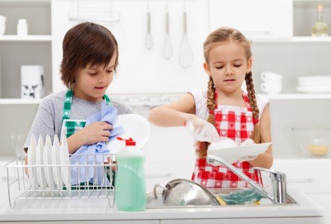 Kids washing the dishes in the kitchen together - helping out wi